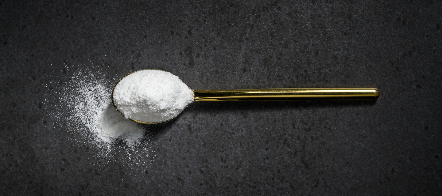 Gold spoon with white powder on a dark surface