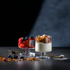 Two glass dishes with dessert on a dark surface with a spotlight effect